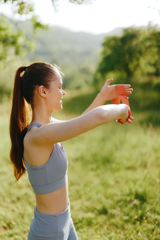 Young female athlete stretching outdoors in athletic wear, showcasing healthy lifestyle and fitness concept amidst greenery