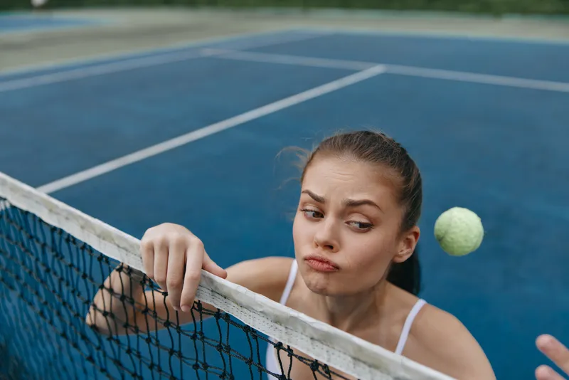 Young female tennis player focused on the ball, displaying determination and concentration while playing tennis on a blue court
