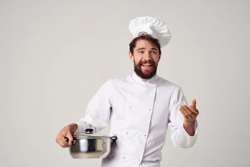 Весёлый повар с кастрюлей в руках работает на кухне