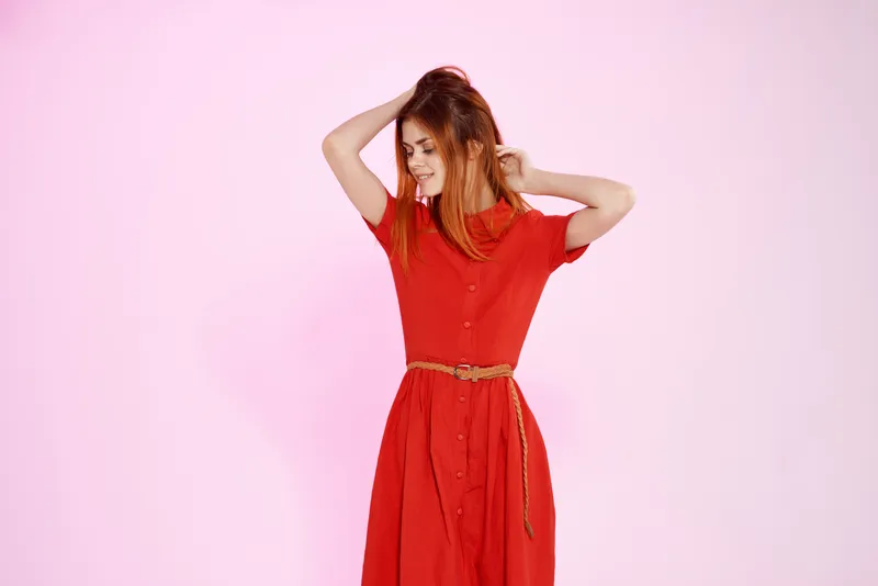 Женщина в красном платье позирует в студии, передавая гламурное настроение и эмоции
