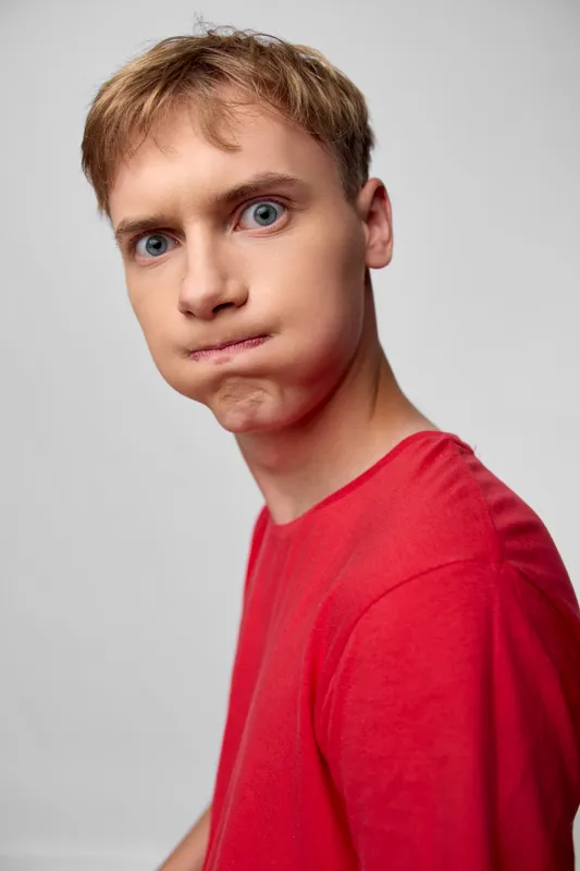 Surprised expression, red shirt, young man, casual scene, candid moment, facial expression, dramatic look, emotion, playful mood, youth, fashion, everyday life, close up, studio shot, emotion
