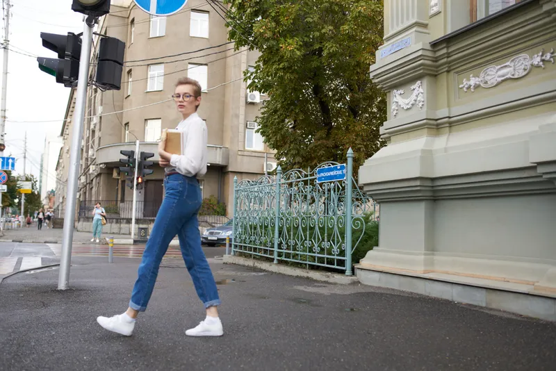 Симпатичная женщина в очках гуляет по городу с книгой в руках, посвящая время образованию