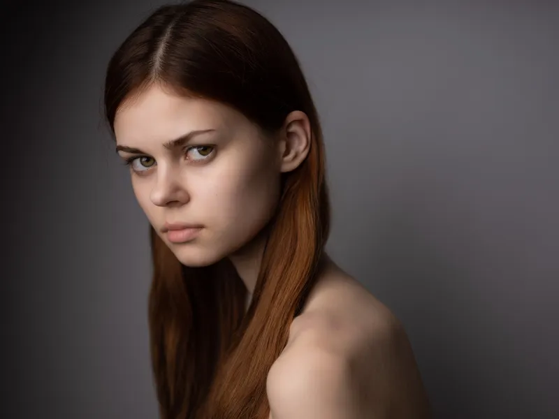 На фотографии изображена симпатичная женщина с уложенными волосами и обнаженными плечами