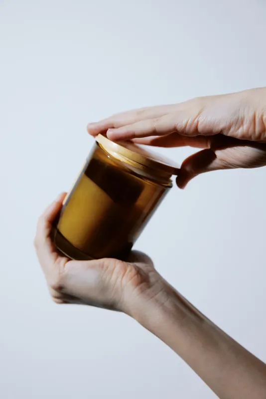 Рука держит банку с мёдом и этикеткой «honey» на белом фоне