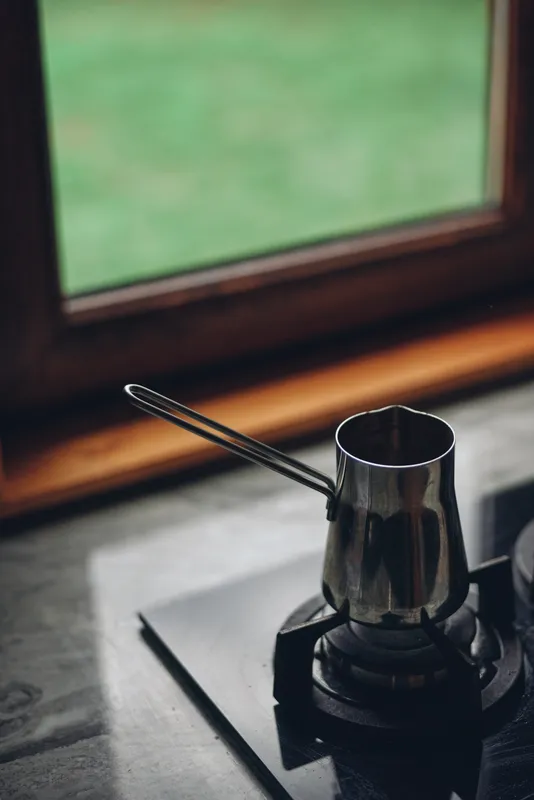 Closeup of a coffee pot on a stove and kettle, metal construction in a rustic kitchen, capturing a warm brew moment ready to pour