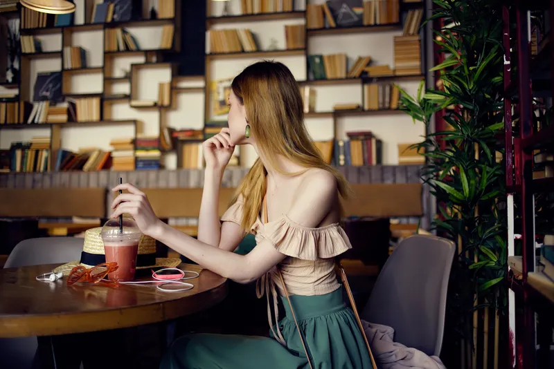 Красивая женщина читает книгу в кафе