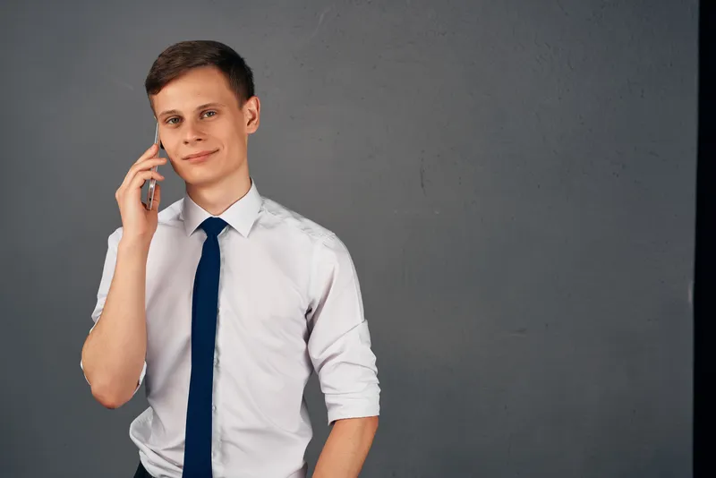 Мужчина в рубашке с галстуком держит в руках телефон, на экране которого отображается сообщение об официальной работе