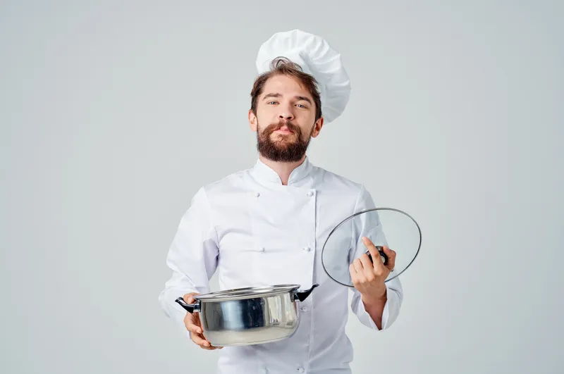 Весёлый шеф-повар-мужчина с кухонной утварью в кулинарной индустрии