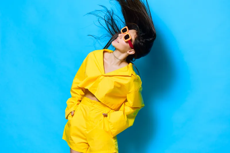 Молодая женщина с длинными волосами в солнечных очках позирует в студии