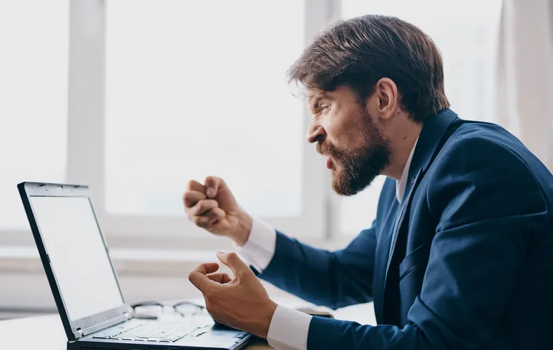 Мужчина сидит за столом перед ноутбуком, профессионально работая в финансовой сети