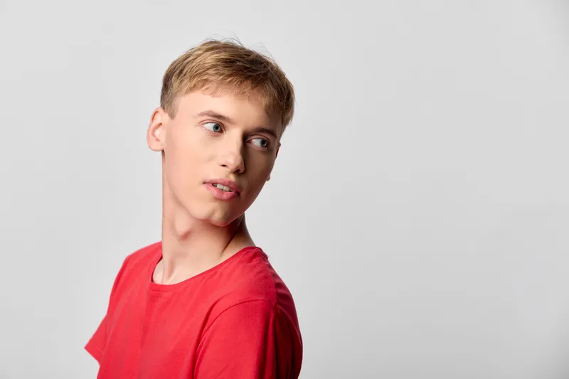 Boy in a bright red t shirt looks to the side against a neutral studio backdrop, casual fashion vibe, clean lighting and simple composition suitable for youth marketing and apparel.