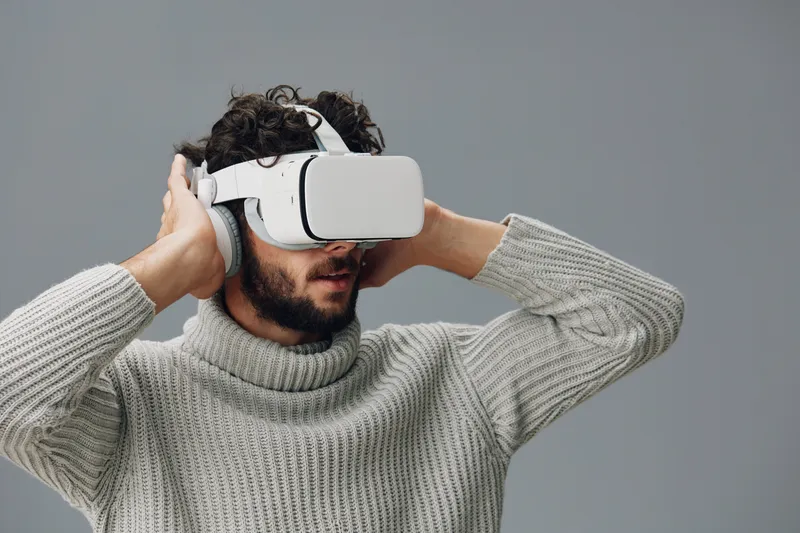 Молодой мужчина смотрит вдаль, на нем современные VR-очки и гарнитура