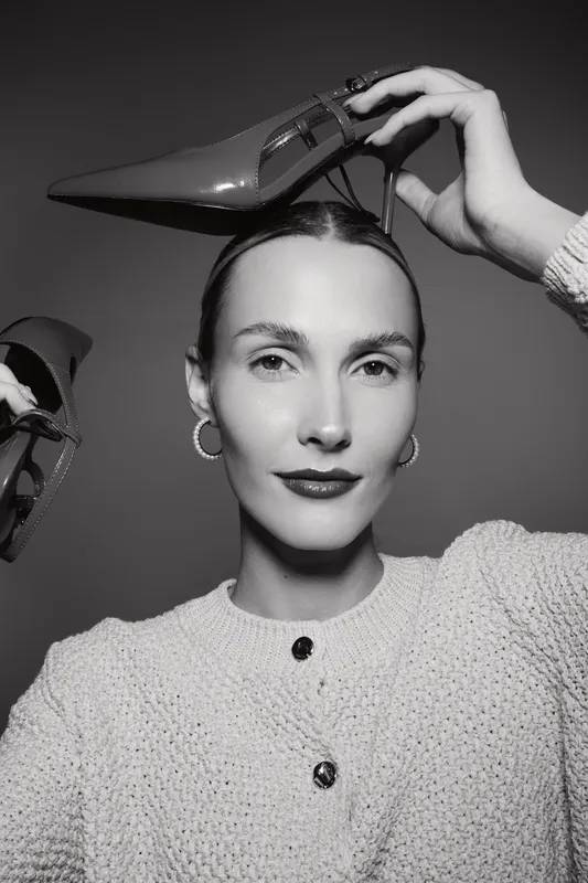 White caucasian woman with light skin poses with high heel shoes near head in studio. Fashion concept for style, elegance, and female portrait with creative footwear accessory.