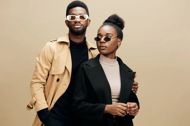 Fashionable African models posing in stylish sunglasses, showcasing modern trends against a warm, neutral backdrop, reflecting confidence and elegance