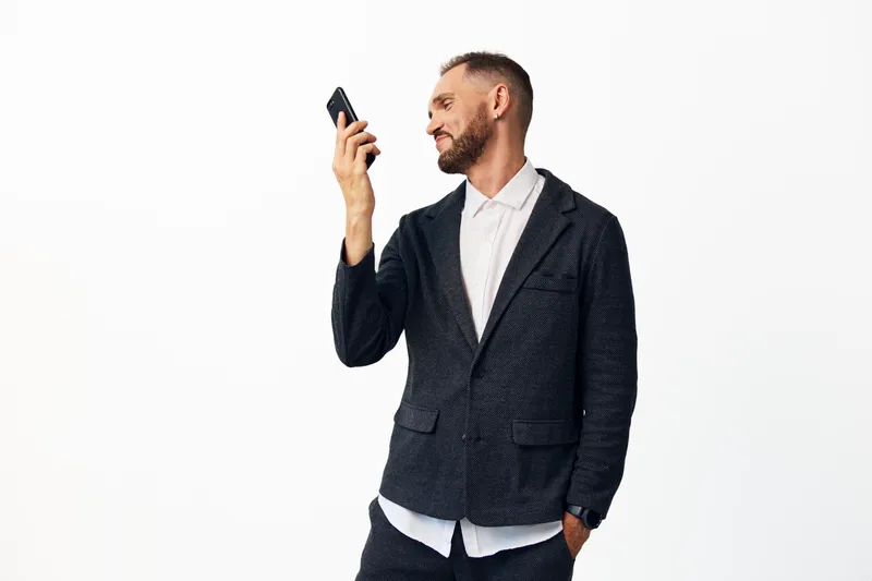 A professional man in a patterned blazer and white shirt checks his smartphone against an isolated colored background, displaying confident, reflective emotion.