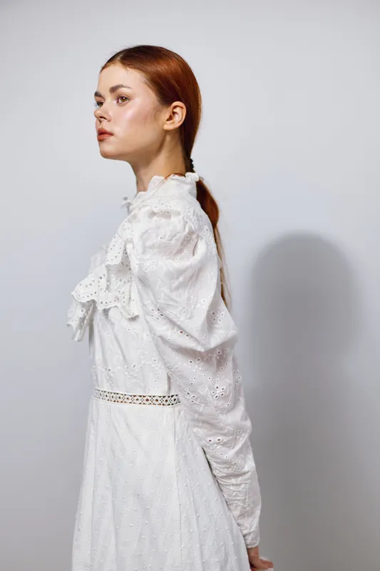 Elegant portrait of a young woman in a white dress, showcasing graceful emotions against a soft white background Perfect for seasonal fashion or beauty contexts