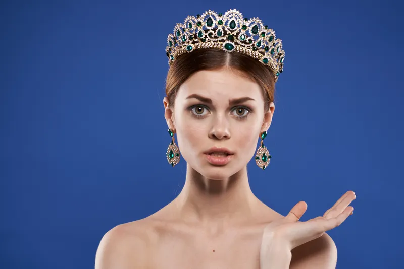 Красивая женщина в короне на голове, с макияжем, модель, жестикулирующая рукой, крупный план, образ жизни