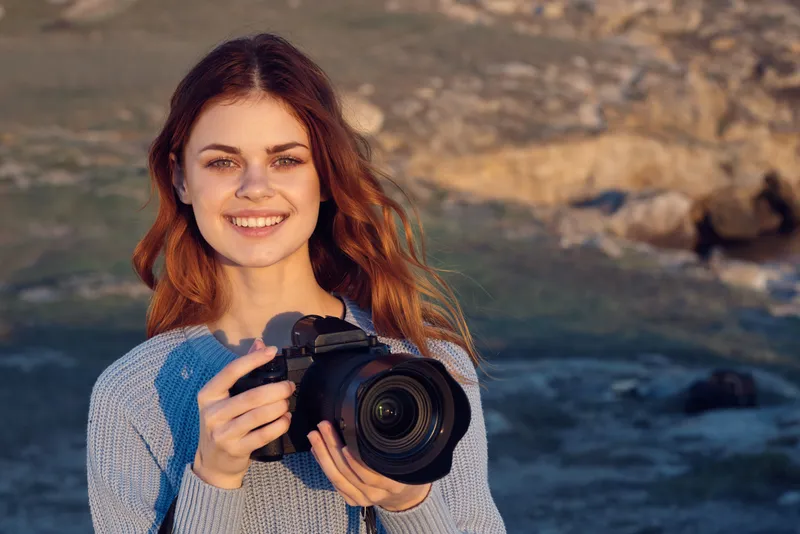 Женщина-туристка с камерой фотографирует пейзаж на природе во время отпуска и путешествия