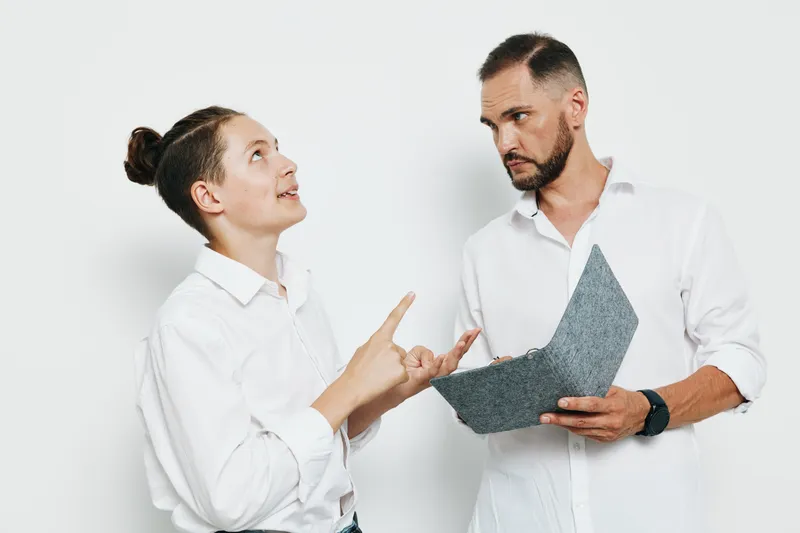 A professional man and colleague discuss a project on a clean white background, showing confident body language and focus, signaling business intent and steady determination.