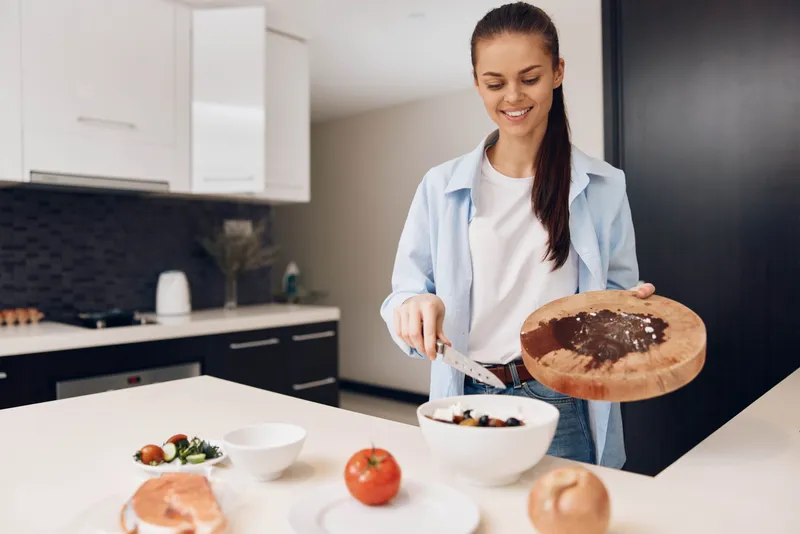 Женщина держит миску с едой перед кухонной стойкой, готовя обед для своей семьи