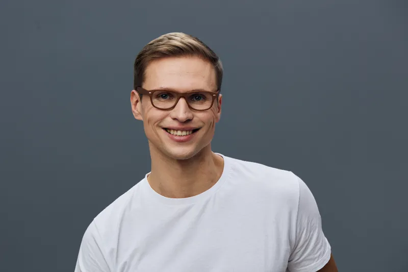 smiling young caucasian man wear glasses white t-shirt look camera isolated on grey background digital nomad remote work concept