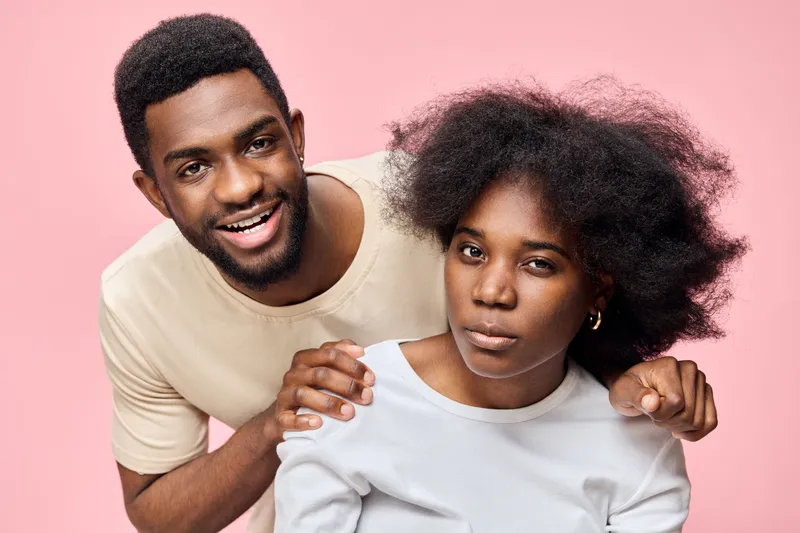 Young Black couple smiling together on a pink background, showcasing confidence and joy, perfect for themes of love and friendship