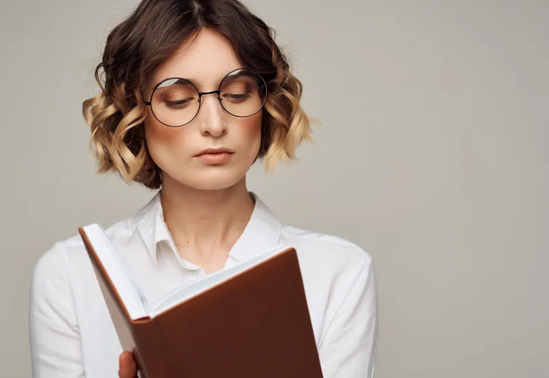 Симпатичная женщина в очках с книгой, элегантный стиль для профессионалов