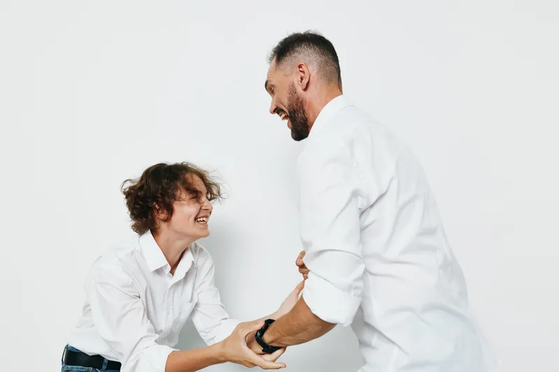 A professional man and colleague share a warm handshake against a clean, colored backdrop, conveying strong business presence, confidence, and optimistic emotion in a corporate setting.