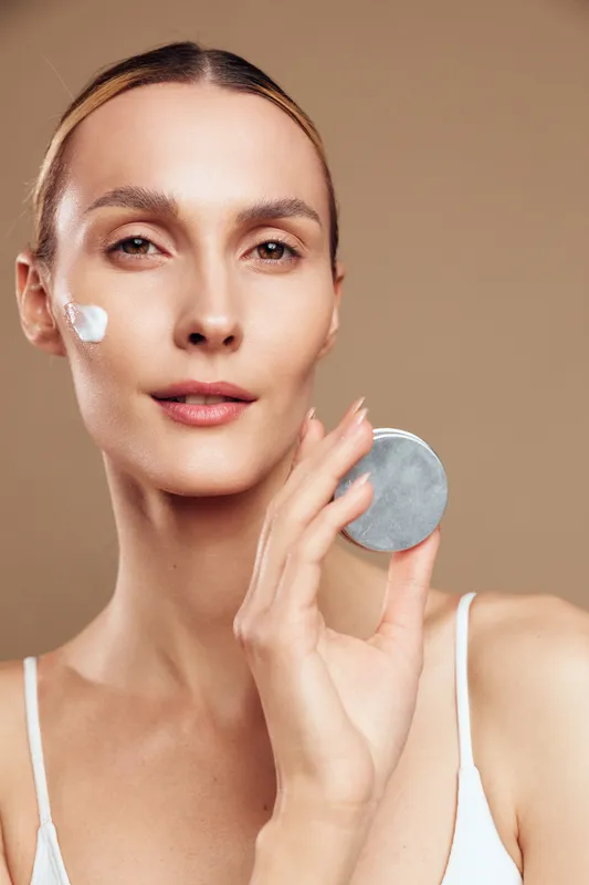 woman face skincare beauty cotton pad closeup portrait, applying gentle cleanser on cheek, calm expression, smooth skin, soft studio light, beige background