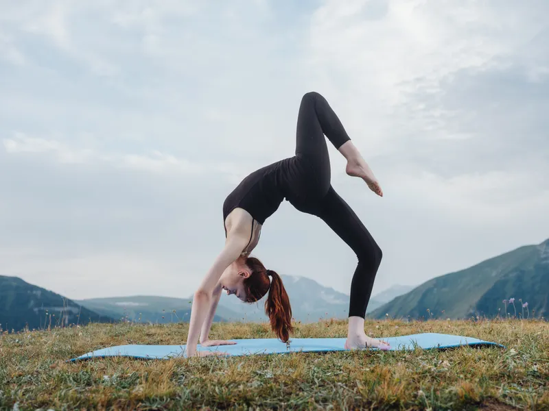 Спортивная женщина в горах занимается йогой и фитнесом на открытом воздухе