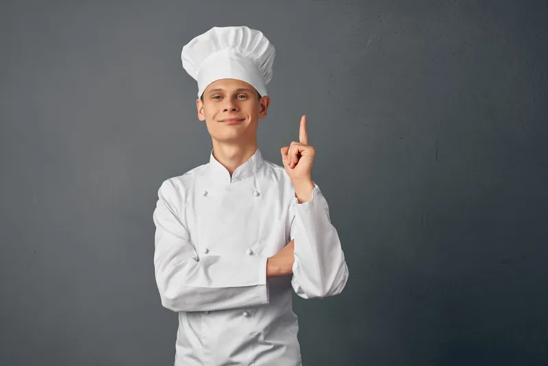 Весёлый мужчина в форме шеф-повара поднимает руку в элитном ресторане
