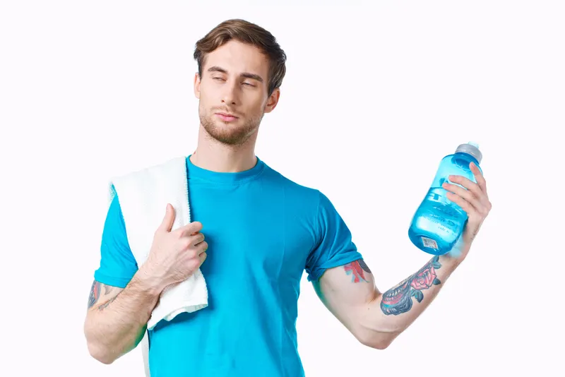 Мужчина в синей футболке с бутылкой воды, здоровье и фитнес