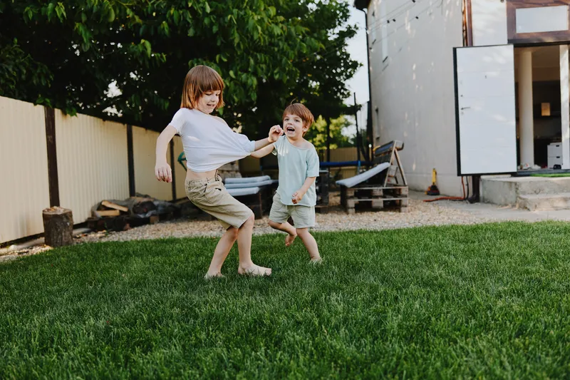 Two joyful boys playing together in a sunny backyard, showcasing their carefree childhood moments and vibrant energy while enjoying the outdoors.