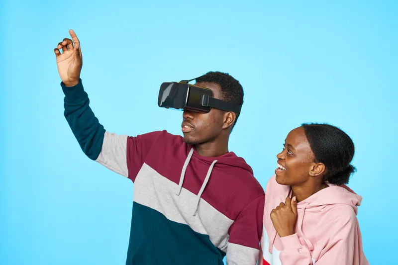 На лицах африканского мужчины и женщины надеты 3D-очки виртуальной реальности на фоне синего плана