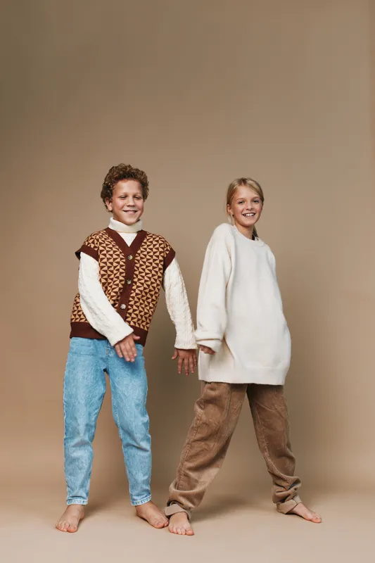 Authentic scene of children in cozy outfits enjoying a playful moment, capturing a lifestyle and school vibe in a candid, natural studio setting with warm tones.