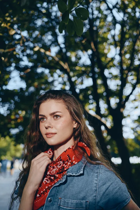 lifestyle woman wearing modern boho-western denim and red bandana, outdoors in natural light with film color effect capturing stylish street style vibe