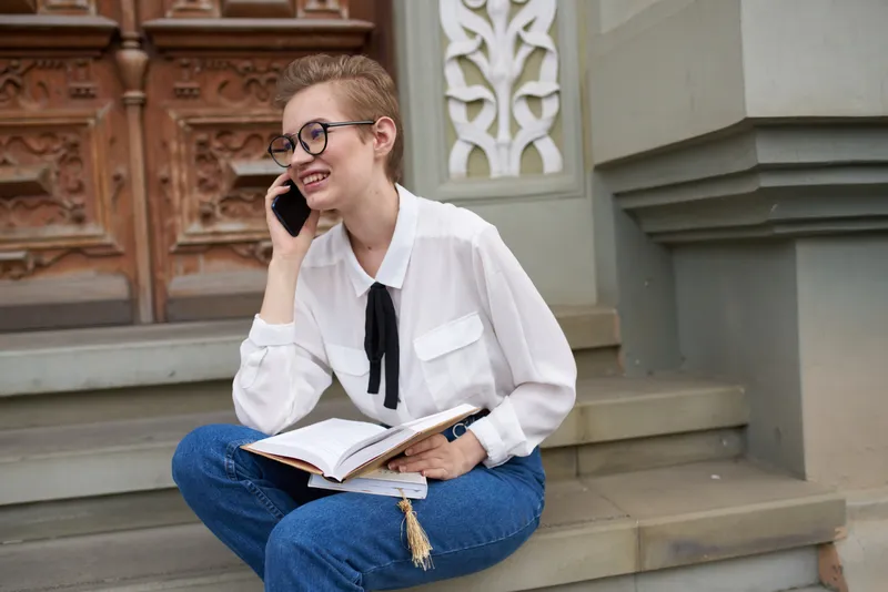 Симпатичная женщина с книгой в руках на улице, чтение и общение