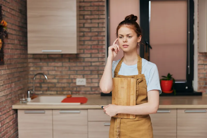 Женщина на кухне в квартире, среди кухонной утвари