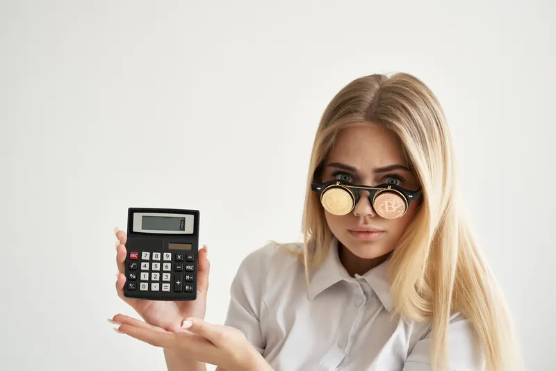 Бизнесвумен с калькулятором в руке и биткоином на изолированном фоне
