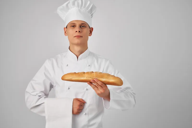 Мужчина в униформе повара, пекарь с буханкой хлеба в руках, свежий продукт