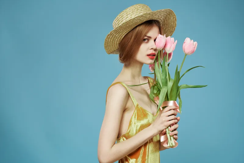 На фотографии изображена женщина с роскошным букетом цветов, которая дарит очаровательную улыбку на фоне голубого неба