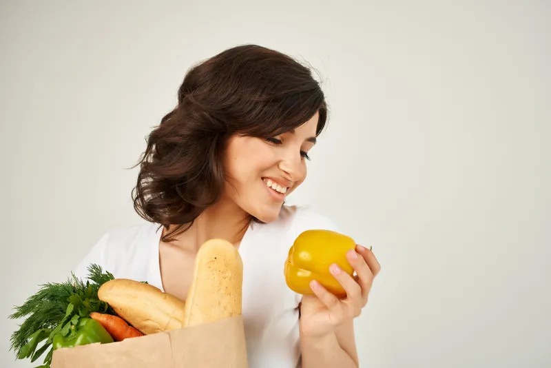 Симпатичная брюнетка в белой футболке с пакетом продуктов здорового питания