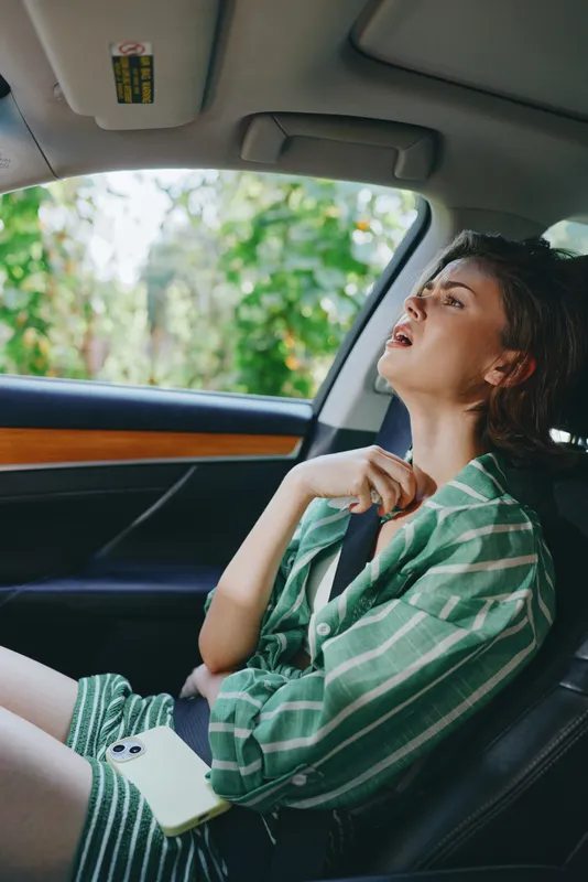 A woman sits in the front passenger seat, wearing a green striped shirt, relaxed pose, natural light highlighting her profile.
