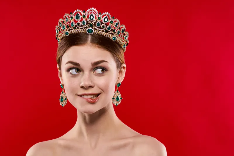 Красивая женщина с роскошными обнаженными плечами, косметика, мода, веселье на красном фоне