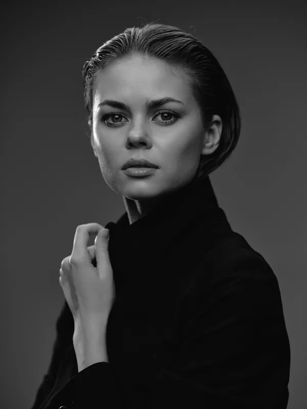 Serious woman portrait in black and white with thoughtful expression and dark clothing.