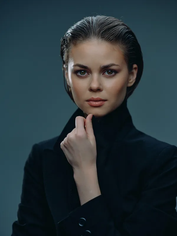 portrait of a serious woman with slicked hair wearing a black outfit in studio lighting