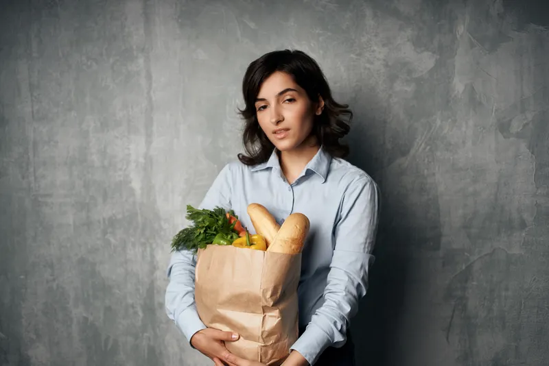 Брюнетка с продуктовым пакетом из супермаркета — овощи, диетическое питание