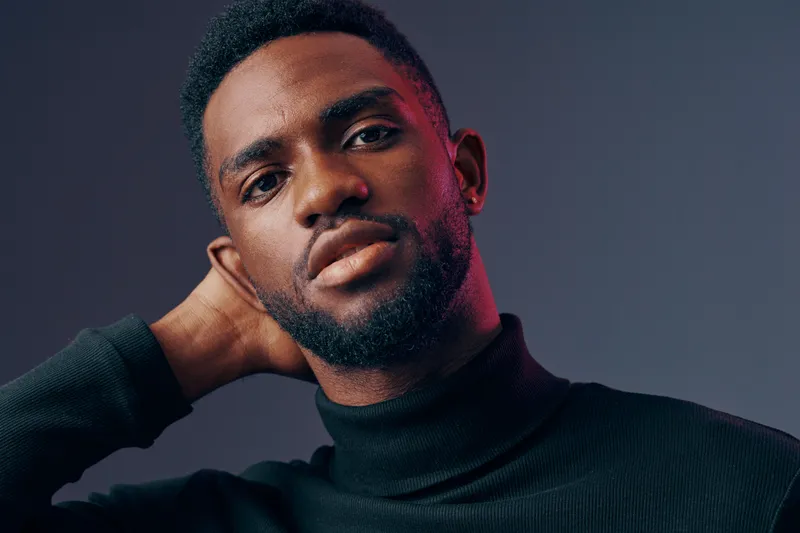 Portrait of a Black male model in a stylish turtleneck, conveying confidence and sophistication, with deep colors and a moody background
