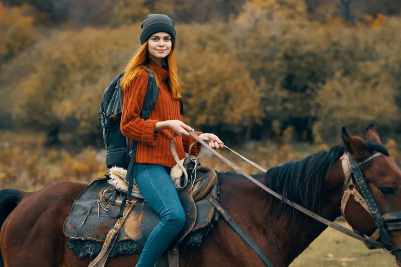 Женщина-туристка верхом на лошади на фоне горного пейзажа