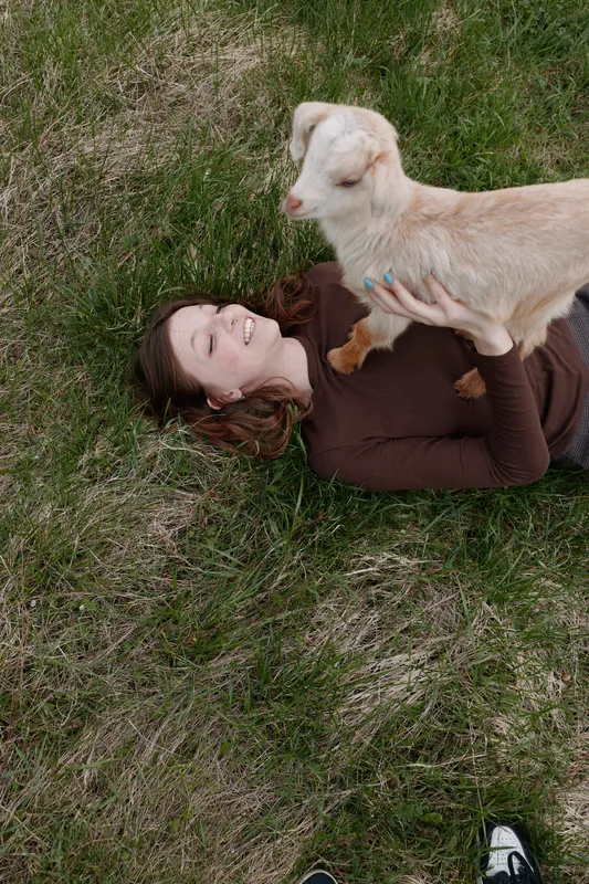 Young woman lies on the grass with a dog resting on her chest, savoring a calm outdoor moment. Cozy, affectionate lifestyle scene highlighting companionship, nature, and relaxing wellness with warm,